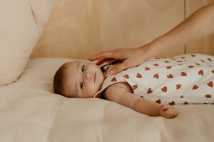 Bébé allongé portant une gigoteuse blanche à cœurs - Les Petites Billes
