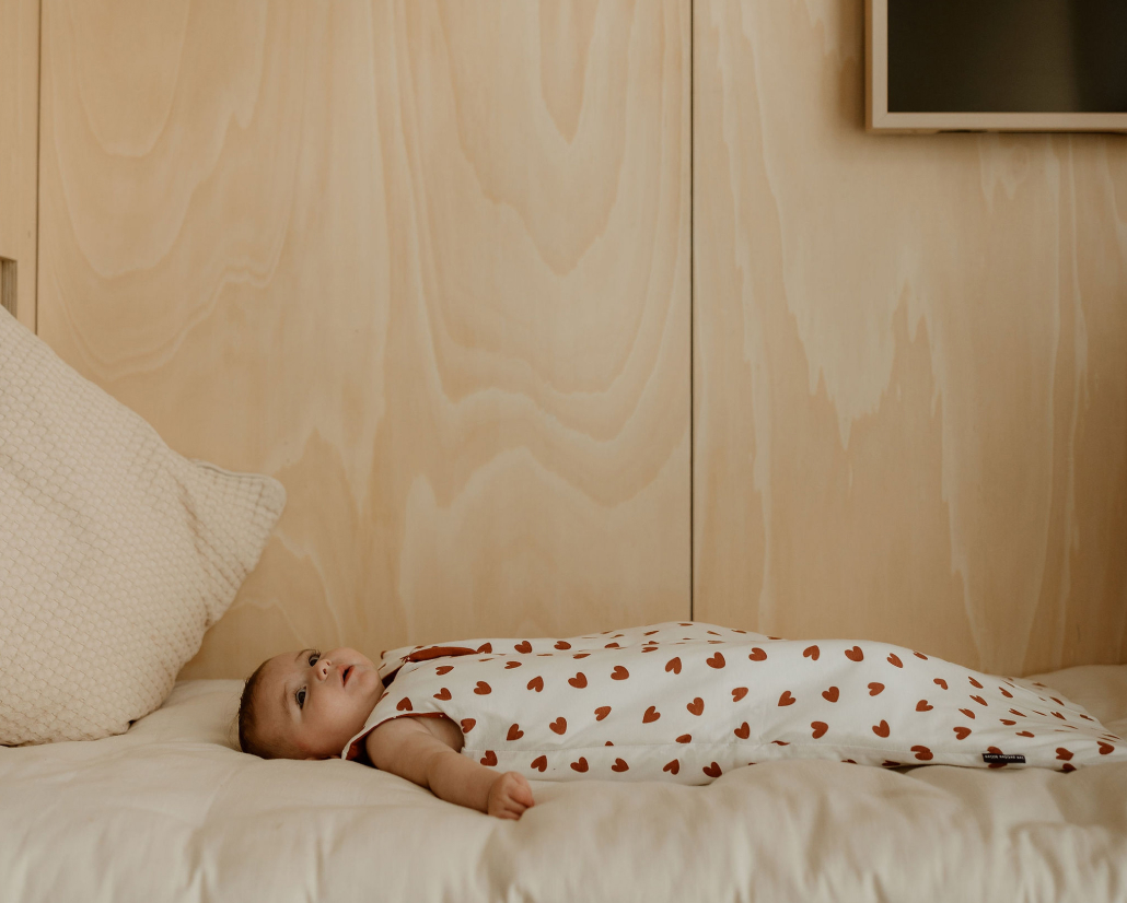 Bébé allongé dans une gigoteuse à motif cœurs, dans sa chambre
